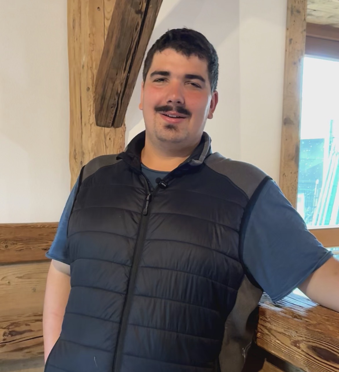 Kilian Schmid vor der Holzwand seiner Werkstatt
